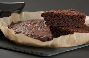 Homebaked Chocolate Brownie In Parchment Paper. Slate Stone.