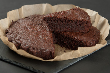 Homebaked Chocolate Brownie In Parchment Paper. Slate Stone.
