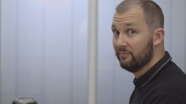 Portrait of a young man looking happy while working at a computer- tracking shot