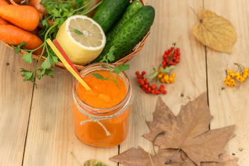 Морковный смузи в стеклянной банке с овощами на деревянном фоне. Здоровое питание.