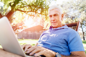 Obraz premium Senior man with notebook sitting in the park