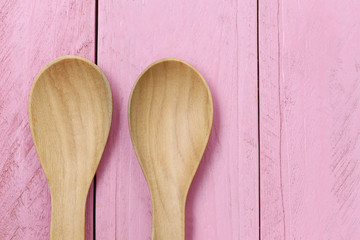 Wooden spoon on pink wood floors.