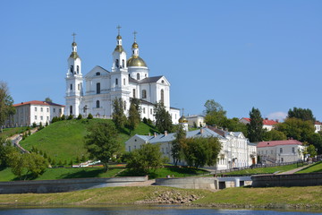 Fototapeta na wymiar beautiful white cathedral with golden domes of the river on a background of blue sky
