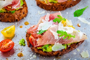 bruschetta with prosciutto, avocado, tomatoes, arugula and cheese
