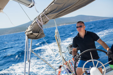 Young sailor skipper manages sailing vessel during regatta race in the open sea.