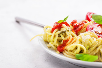Homemade spaghetti pasta with avocado, tomato and basil sauce, closeup