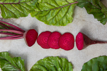 Raw beetroot sliced with leaves on rustic board . Top view with copy space.