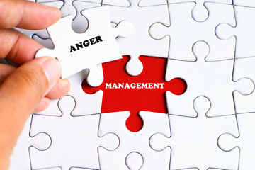 "MANAGEMENT" word on missing puzzle with a hand hold a piece of "ANGER" word puzzle want to complete it - business and finance concept