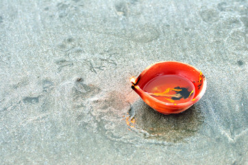 Traditional Diwali lamps and candles lit on the sand beach. Selective focus, shallow DOF and visible noise due to low light.