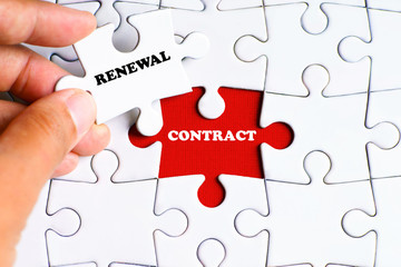 "CONTRACT" word on missing puzzle with a hand hold a piece of "RENEWAL" word puzzle want to complete it - business and finance concept
