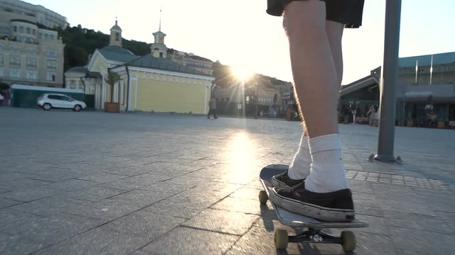 Skateboarder in the street. Person on skateboard in slow-mo. Towards the sun. Energy of young generation.
