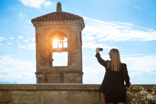 Silhouette Of Woman Taking Photo With Smart Phone Of Old Bell Tower At Sunset Lights - Concept Of Tourism And New Mobile Technologies