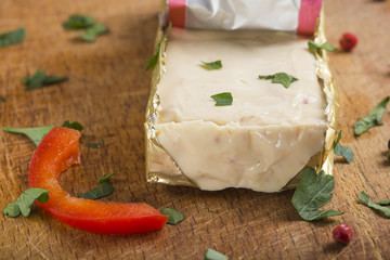 Block of melted cheese in golden foil with herbs