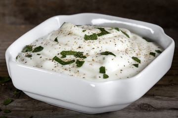 Bowl of sour cream or yogurt with herbs and black pepper in bowl