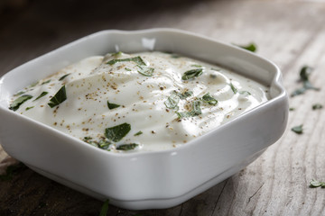 Close up of sour cream or yogurt with herbs and black pepper