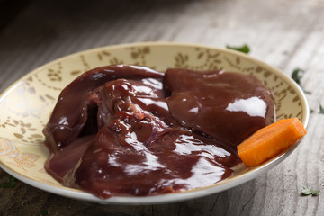 Chicken raw liver in plate on wooden