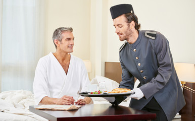 Page bringt Mann Frühstück ins Hotelzimmer