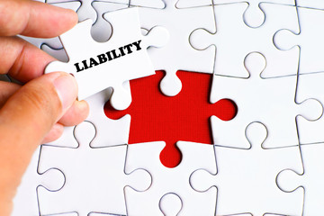 Missing puzzle with a hand hold a piece of "LIABILITY" word puzzle want to complete it - business and finance concept