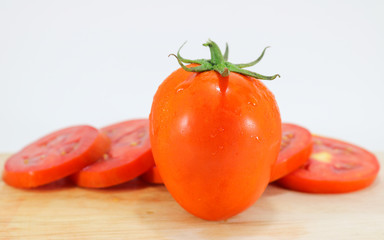 Tomato slice on wood chopping block white background isolated.