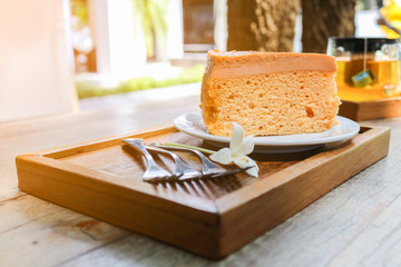 Cake on plate with fork and flower on wood table.