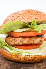 Hamburger with fried onion, tomatoes, iceberg lettuce on a wooden board