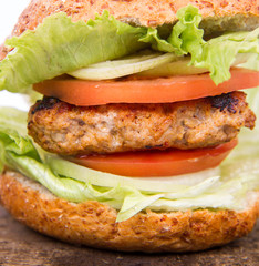 Hamburger with fried onion, tomatoes, iceberg lettuce on a wooden board