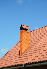 Red Metal Roof with Brick Chimney. Metal Roofing Construction.