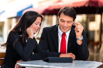 Businessman and Businesswoman Discussing Digital Tablet at Sidew