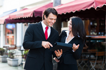 Businessman and Businesswoman chatting outside cafe with digital