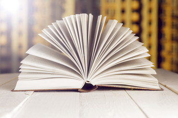 Open book on wood planks over abstract light background
