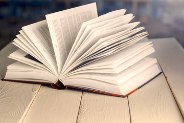 Open book on wood planks over abstract light background
