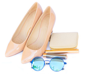 Nude colored high heels still life with wallet, sun glasses and lipstick isolated on white background