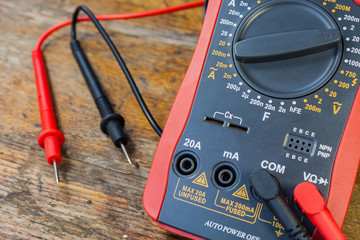 Digital multimeter with the connected probes on a table in a workshop