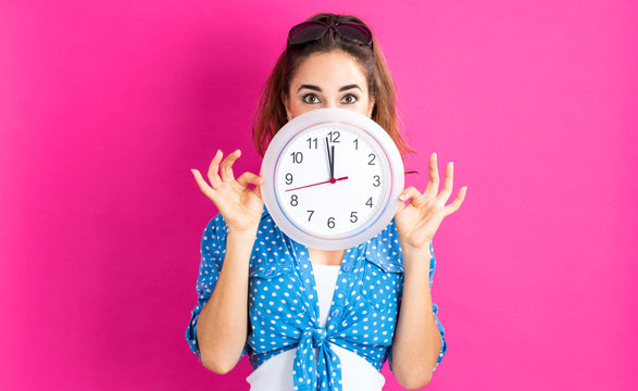 Woman holding clock showing nearly 12