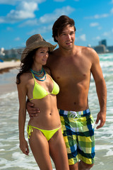 Attractive young couple man and woman standing in surf on South Miami Beach Florida with hotels in background