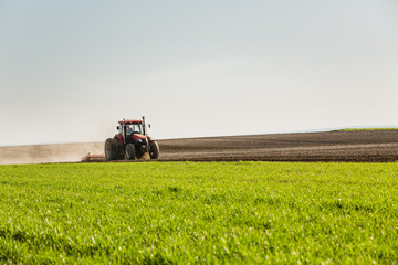 Obraz premium Farmer in tractor preparing land with seedbed cultivator