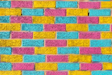 Brick wall painted in bright yellow, blue and pink colors