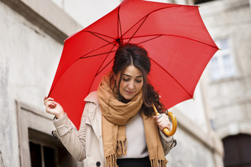 Woman with red umbrella walking in the old town.