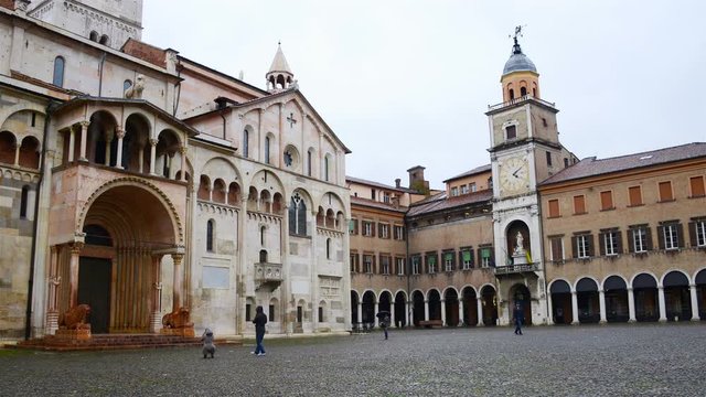 Square in front of Cathedral in Modena, Italy during the cloudy rainy day. Time-lapse of few people with umbrellas
