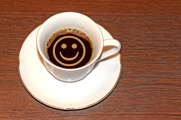 Cup of coffee and a smiley face . The concept of morning good mood .