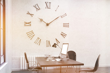 Side view of sunlit office with large wall clock