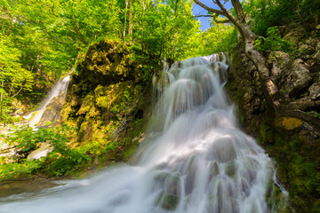 Beautiful waterfalls in spring in the forest, on a bright sunny day