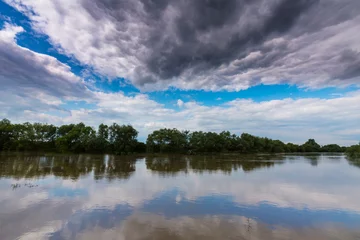 Foto op Canvas Ominous stormy sky over natural flooded river © Calin Tatu