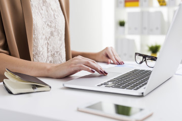 Girl in beige cardigan with red nails is typing