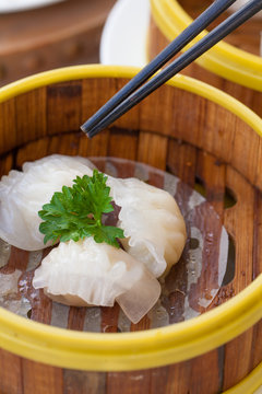 Chinese steamed white dumpling or Hakau Dim sum stuffed with minced shrimp decorated in bamboo made steamer local style with chopsticks.