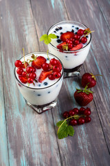 Homemade yogurt with berries on the old wooden background.