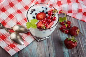 Homemade yogurt with berries on the old wooden background.