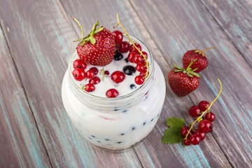 Homemade yogurt with berries on the old wooden background.