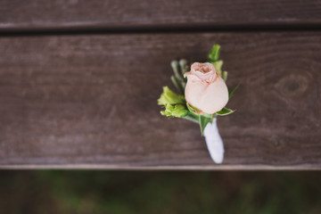 boutonniere with pink rose on wooden background