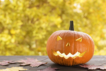 Naklejka na ściany i meble halloween pumpkin, jack-o-lantern on wooden table with autumn bokeh background. image with copy space